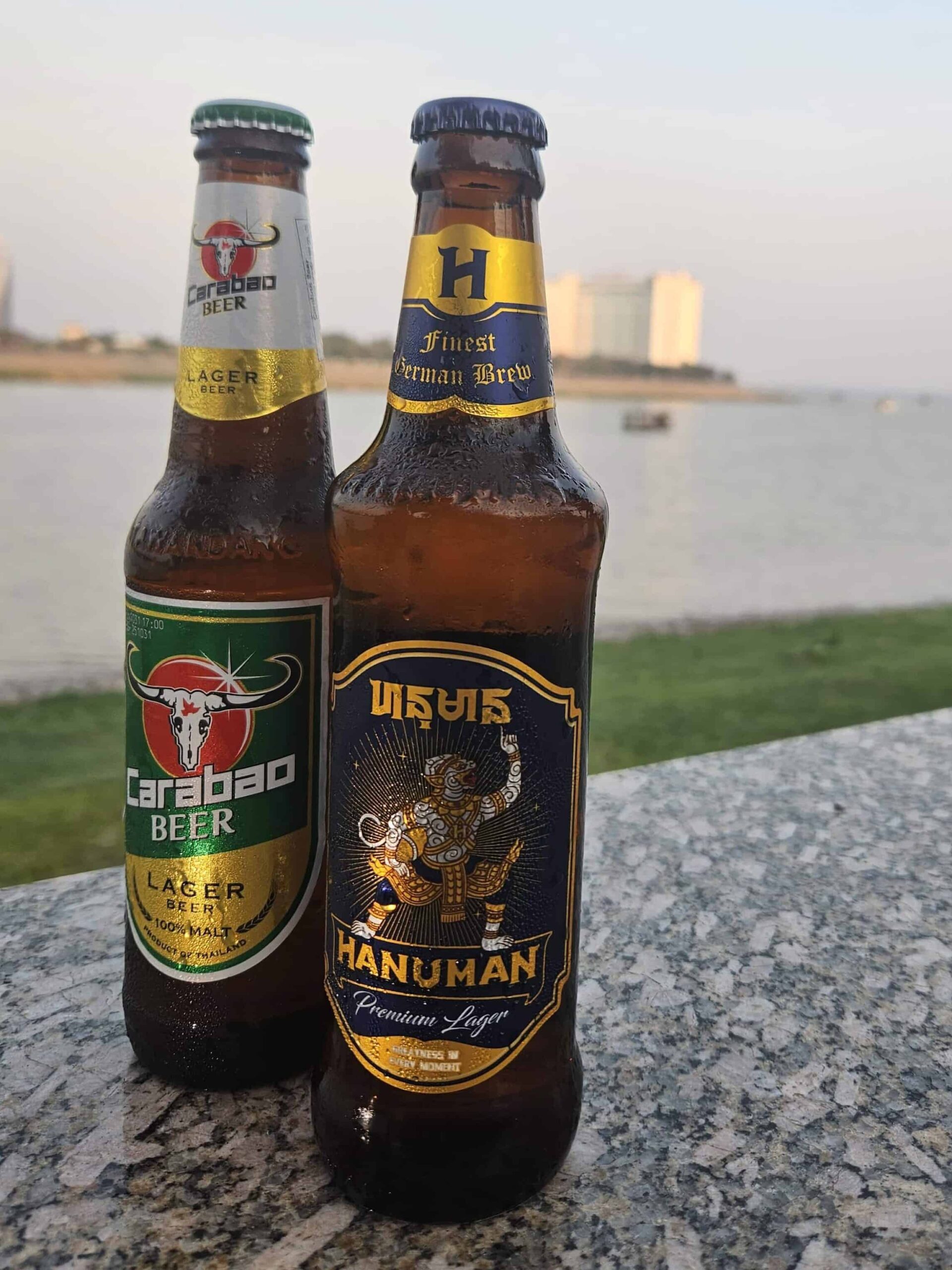 Bottle of Carabao Beer and bottle of Hanuman Premium Lager with Mekong River in background, Phnom Penh, Cambodia