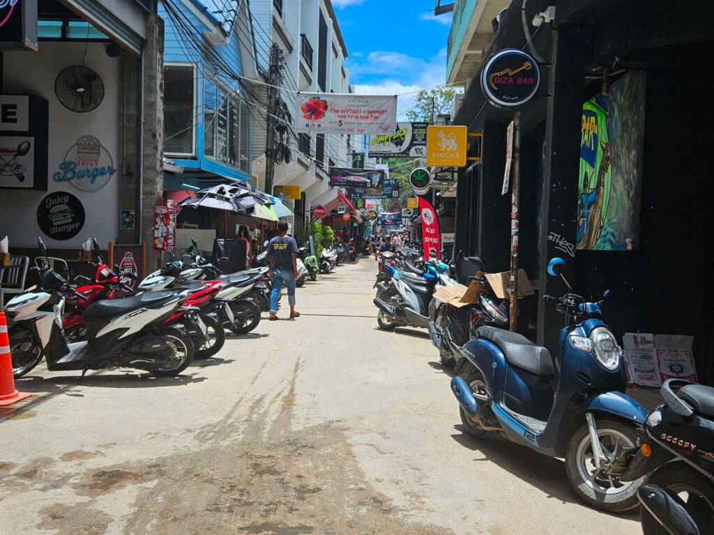Scooters lining a road outside a rental shop at Sairee beach Koh Tao 