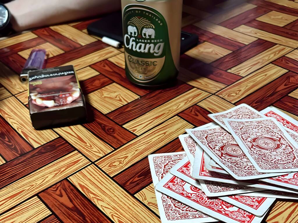 Backpackers playing cards with locals at Thai homestay