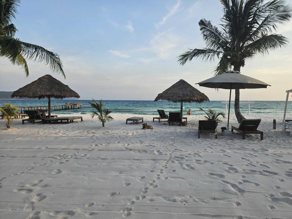 A backpacker enjoying a pristine white-sand beach on Redang, Malaysia, emphasizing the need for slow travel and relaxation during a 6-month Southeast Asia itinerary.