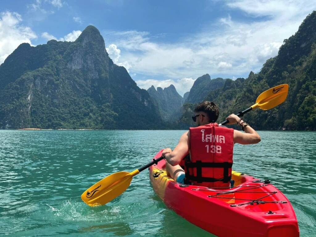 Solo backpacker kayaking on Cheow Lan Lake in Khao Sok National Park, Thailand, embodying the personal reward and transformation achieved after completing a 6 month Southeast Asia itinerary.