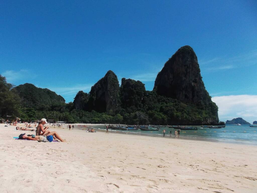 Iconic Railay Beach in Thailand with towering limestone karst cliffs and longtail boats, a must-see stop on your 6 month itinerary
