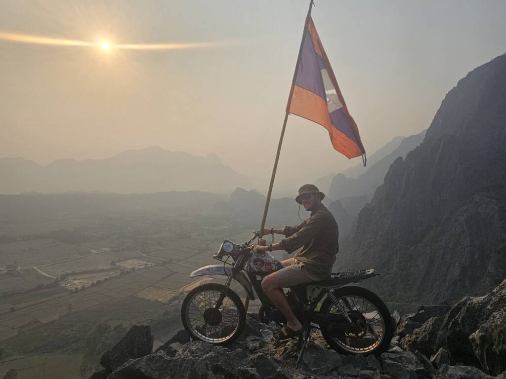 Backpacker on a motorbike overlooking Vang Vieng, a highlight of the Northern Laos loop on a 6 month itinerary.