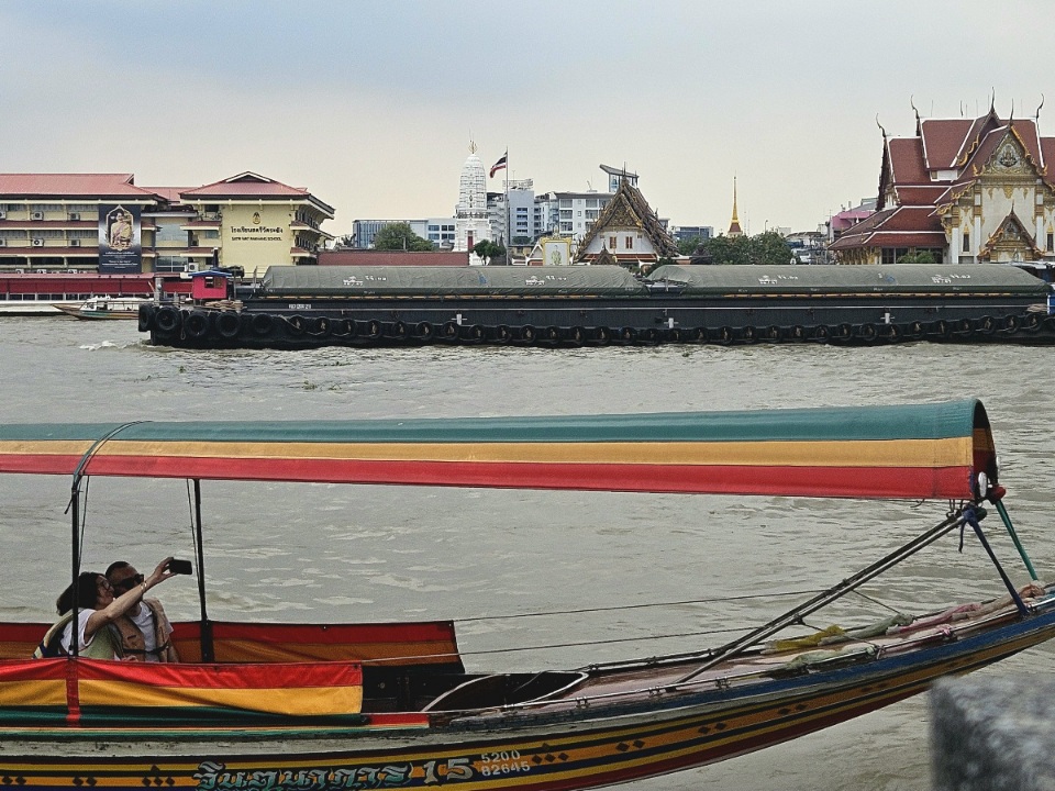 Longtail boat and barge on Chao Phraya river in Bangkok