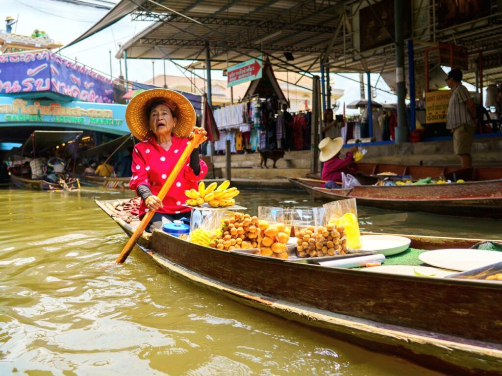 Woman selling fruit from boat at Bangkok Floating Market day trip